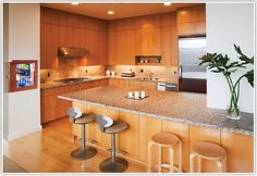 a kitchen with two bar stools next to a counter top and an island in the middle