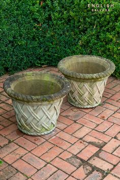 two planters sitting on top of a brick walkway