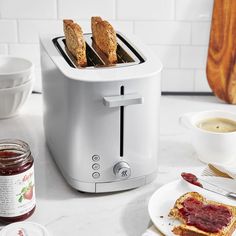 two slices of toast sitting on top of a white counter next to jam and butter