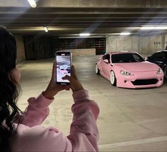 a woman taking a photo of two cars in a parking garage with her cell phone