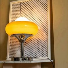 a yellow lamp sitting on top of a table next to a wall mounted light fixture