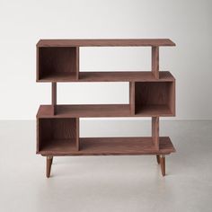 a wooden shelf sitting on top of a white floor next to a wall with two shelves