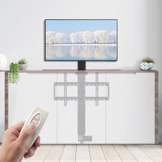 a person holding a remote control in front of a flat screen tv on a stand