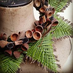 a close up of a hat on a mannequin with pine cones and leaves