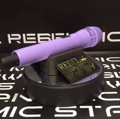 a purple hair dryer sitting on top of a black table next to a sign