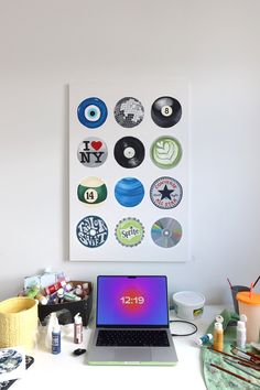 a laptop computer sitting on top of a white desk next to a wall with various stickers