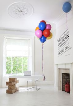 there is a bunch of balloons floating in the air over a room with a fireplace