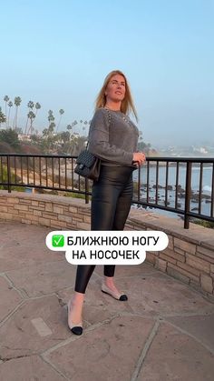 a woman is standing in front of a fence with her hands on her hips and looking at the camera