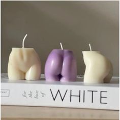 three candles sitting on top of a book with the words white in front of them