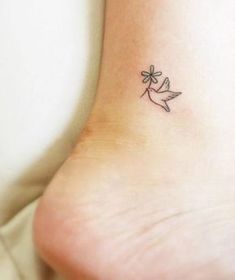 a small tattoo on the ankle of a woman's foot with a bird flying above it