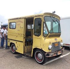 an old yellow food truck parked in a parking lot with people standing around and looking at it