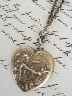 a silver heart shaped locke sitting on top of a piece of paper with writing in the background