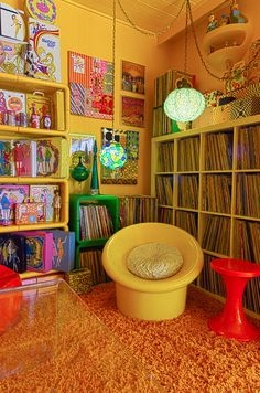 a room filled with lots of records on shelves and colorful chairs in front of them