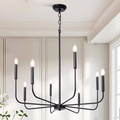 a black chandelier hanging from the ceiling in a dining room with white walls