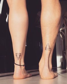 two people with matching tattoos on their legs standing next to each other in front of a door