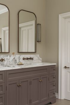 a bathroom with double sinks and two mirrors on the wall next to eachother