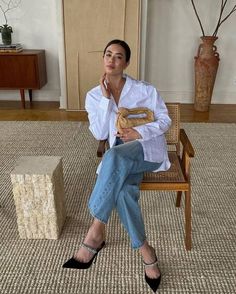 a woman is sitting on a chair and talking on the phone while holding a purse