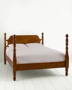 a wooden bed frame with white sheets and pillows