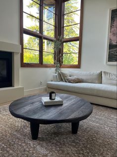 a living room with a couch, coffee table and large window in it's center