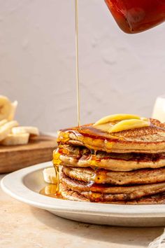 a stack of pancakes being drizzled with syrup