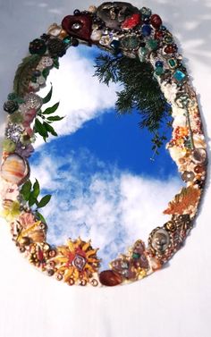 there is a mirror made out of shells and other things on the ground with a sky in the background