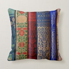 four decorative books are lined up on a pillow that has been placed in front of a white wall