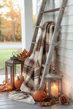 a porch decorated for fall with pumpkins, candles and blankets