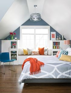 an attic bedroom with blue walls, white bedding and orange pillows on the bed