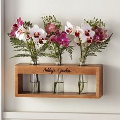 three vases filled with flowers sitting on top of a shelf