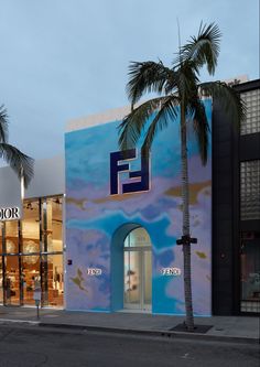 a palm tree stands in front of a building that is painted blue and has the e logo on it