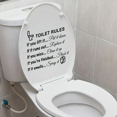 a toilet with the lid up and rules written on it in a bathroom stall next to a sink