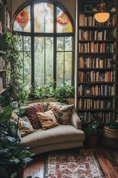 a living room filled with lots of books and plants next to a large arched window