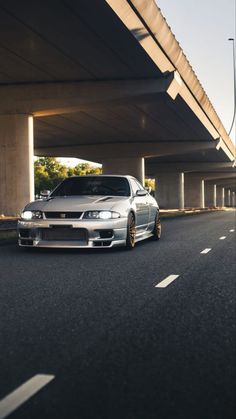 a silver car parked on the side of a road next to a highway overpass