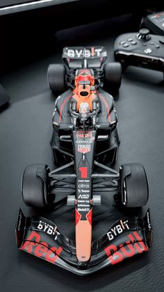 a red and black race car on display with remotes in the backgroud