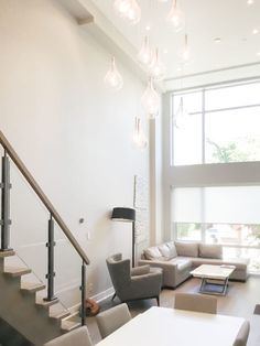 a living room filled with furniture next to a large window and a stair case in front of it