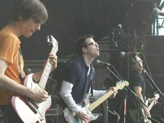 two young men are playing guitars on stage