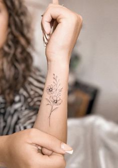 a woman with a flower tattoo on her arm pointing to the side while she is sitting down