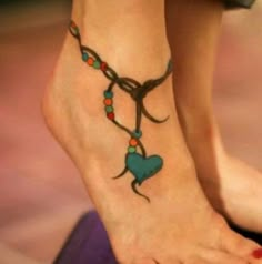 a woman's foot with a cross and heart tattoo on the bottom of it