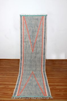 a blue and orange rug with fringes on top of a wooden floor next to a white wall