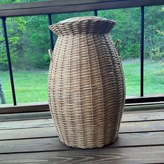 a large wicker vase sitting on top of a wooden table next to a window