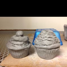 two cupcakes sitting on top of a table covered in frosting