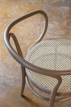 a chair that is made out of wicker and has a bent back design on the seat