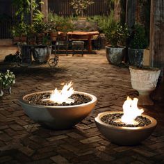 two fire bowls sitting on top of a brick patio