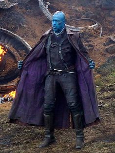 the blue man is standing in front of a fire