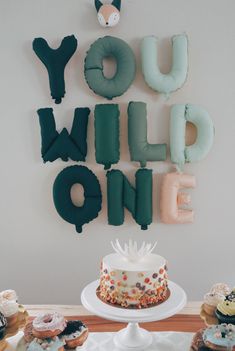 a cake and cupcakes on a table with the words you wild one spelled out