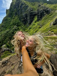 two beautiful young women sitting on top of a mountain