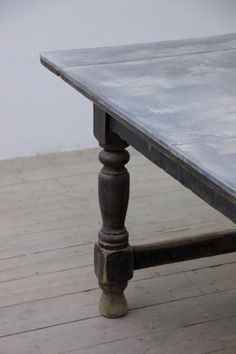 an old wooden table sitting on top of a hard wood floored floor with no one around it