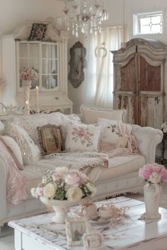 a living room filled with white furniture and lots of flowers on the coffee table in front of it