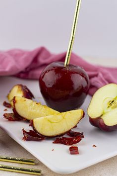 an apple sliced in half and sitting on a white plate next to some gold utensils