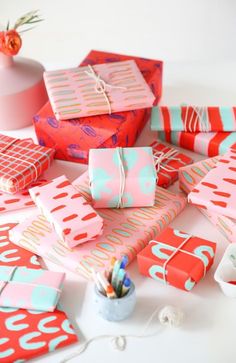 many wrapped presents are on the table with pens and pencils in front of them